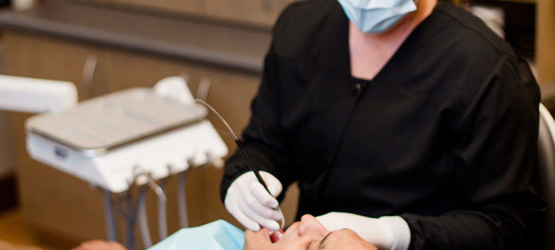 A dental hygienist performing a periodontal disease screening